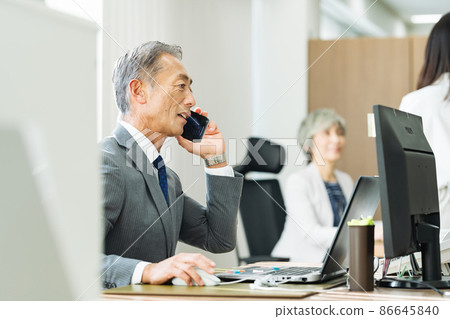 一個 50 多歲的男人在辦公室做辦公桌工作 一個 50 多歲的男人在辦公室做辦公桌工作 86645840