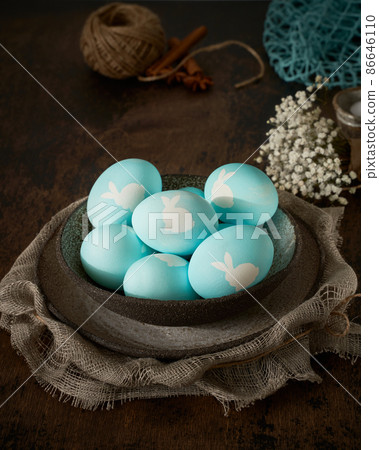 Unusual Easter on dark background. Ceramic brown bowl with blue eggs. Darkness, rays of sunlight Unusual Easter on dark background. Ceramic brown bowl with blue eggs. Darkness, rays of sunlight 86646110