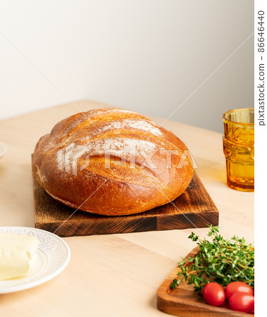 Whole loaf of freshly baked white wheat bread on wooden board on home kitchen table 86646440