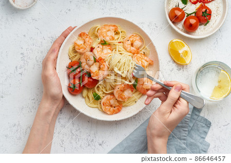 Pasta bavette with fried shrimps, bechamel sauce. Woman hands in frame, girl eats pasta, top view Pasta bavette with fried shrimps, bechamel sauce. Woman hands in frame, girl eats pasta, top view 86646457