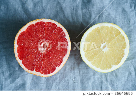 Two halves of red and white grapefruit, bright circles on a dark gray linen background Two halves of red and white grapefruit, bright circles on a dark gray linen background 86646696