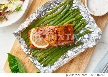 Foil pack dinner with red fish. Fillet of salmon with asparagus. Oven-baked hot dinner Foil pack dinner with red fish. Fillet of salmon with asparagus. Oven-baked hot dinner 86646763
