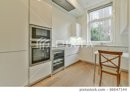 Stylish kitchen room with white wooden table and a brown wooden chair Stylish kitchen room with white wooden table and a brown wooden chair 86647144
