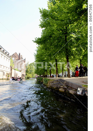 Bruges' lush walks seen from a canal cruise ship Bruges' lush walks seen from a canal cruise ship 86647566