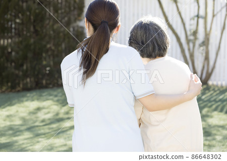 Female caregiver supporting senior women 86648302