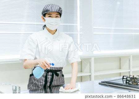 A woman in a cook coat who disinfects and cleans the kitchen 86648631