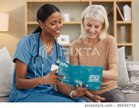 Getting the vaccine or getting the virus...your choice. Shot of a doctor reading a pamphlet about Covid-19 on the sofa at home. 86648738