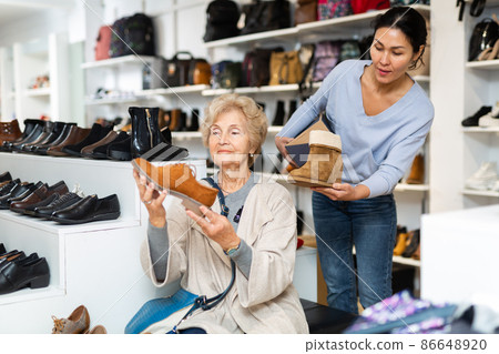Saleswoman helping granny to select new shoes Saleswoman helping granny to select new shoes 86648920