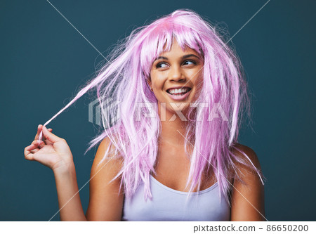 Wherever you go, take your own sunshine with you. Studio shot of a beautiful young woman posing with a playful pink wig against a blue background. 86650200