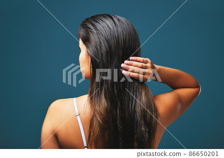 My scars-my best attire. Stunning, my dress of hellfire. Rearview studio shot of a beautiful young woman posing against a blue background. 86650201