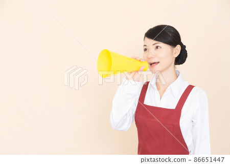 一個穿著圍裙的女人拿著擴音器 一個穿著圍裙的女人拿著擴音器 86651447