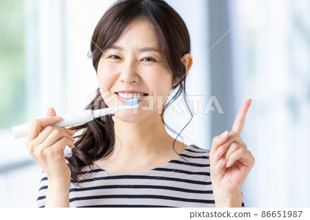 A woman trying to brush her teeth with an electric toothbrush 86651987