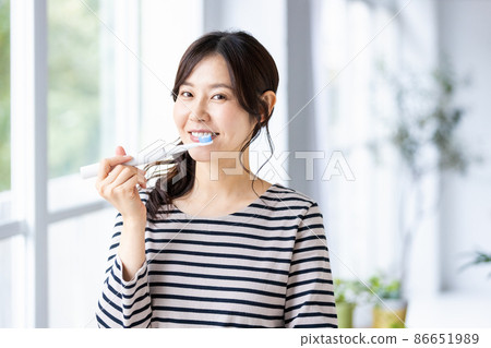A woman trying to brush her teeth with an electric toothbrush A woman trying to brush her teeth with an electric toothbrush 86651989