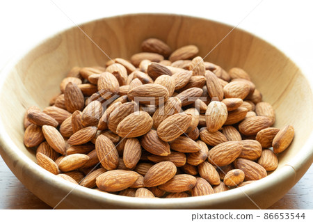 Almonds in brown wooden bowl on wooden table background Almonds in brown wooden bowl on wooden table background 86653544