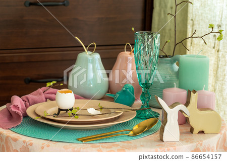 Spring table set for Easter - a chicken egg and a twig with the first leaves on a plate Spring table set for Easter - a chicken egg and a twig with the first leaves on a plate 86654157