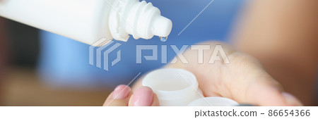 Woman pouring lens liquid into plastic container closeup Woman pouring lens liquid into plastic container closeup 86654366