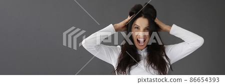 Aggressive young woman screaming and holding head with hands portrait Aggressive young woman screaming and holding head with hands portrait 86654393