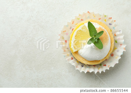 Tasty lemon cupcake on white textured table Tasty lemon cupcake on white textured table 86655544