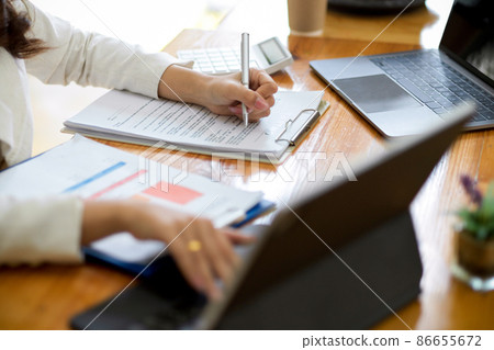 Businesswoman working on tablet and filling document form Businesswoman working on tablet and filling document form 86655672