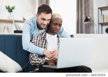 Multiracial men in love using laptop at home Multiracial men in love using laptop at home 86658404