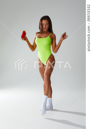 Sporty woman eating unhealthy food on light background. Diet concept 86658582