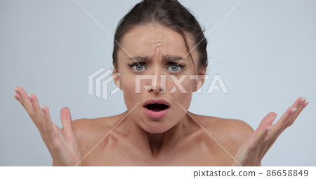 Close-up portrait of young shocked, surprised woman standing isolated over gray background while looking camera. Wow face expression. 86658849