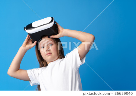 Girl with virtual reality glasses on blue background. Girl with virtual reality glasses on blue background. 86659040