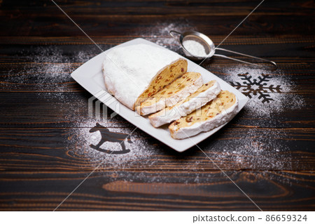 Sliced Traditional Christmas stollen cake with marzipan and dried fruit on wooden background Sliced Traditional Christmas stollen cake with marzipan and dried fruit on wooden background 86659324