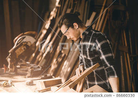 The carpenters man high experienced wood worker making furniture. master of woodcraft male looking at workpiece closeup with fine detail. The carpenters man high experienced wood worker making furniture. master of woodcraft male looking at workpiece closeup with fine detail. 86660330