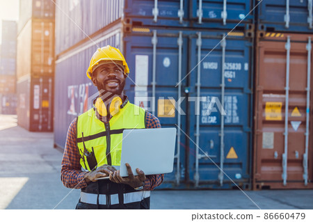 Black African staff workerworking in cargo shipping logistic port with laptop computer. 86660479
