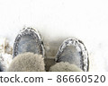 Warm winter women's boots of gray color with fur on a background of snow. 86660520