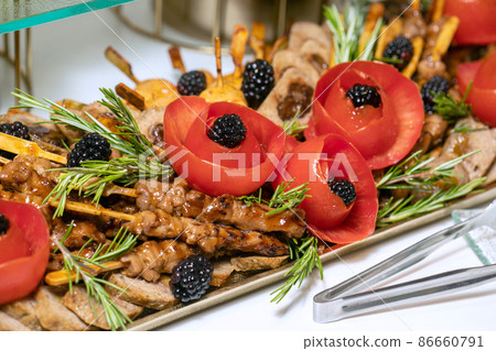 Shashlik or shish kebab prepared on barbecue grill over hot charcoal with grilled vegetables. Grilled pieces of pork meat on metal skewers. 86660791