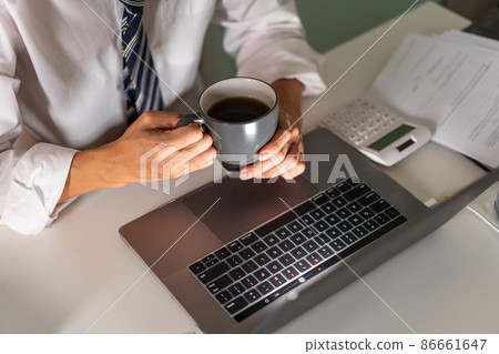Overwork Concept An office man who works late drinking a cup of coffee while concentrating on his work on the notebook 86661647