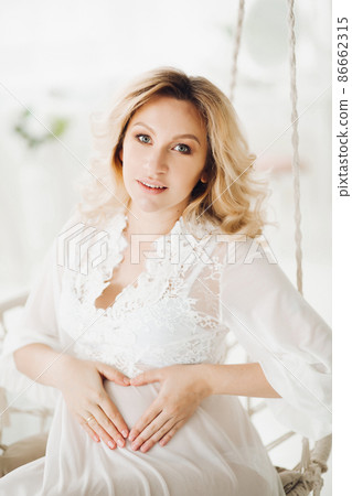Beautiful blonde pregnant woman sitting at swing 86662315