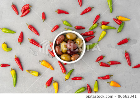 Chili peppers and marinated olives on gray background Chili peppers and marinated olives on gray background 86662341