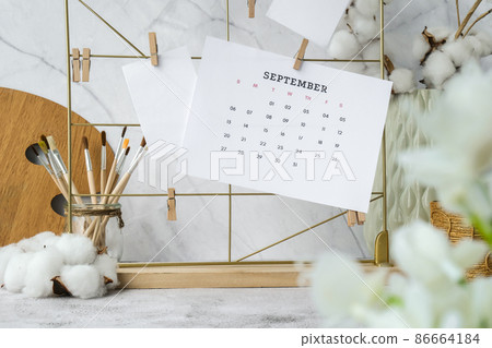 SEPTEMBER CALENDAR cards and posters mock ups on grid board. Copy space. Home office desktop. Freelance bloggers workplace. Brushes and palette 86664184