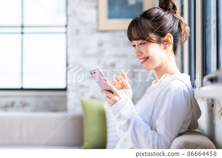 年輕女子在客廳看智慧型手機 年輕女子在客廳看智慧型手機 86664458