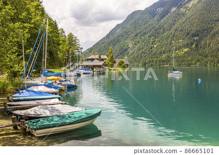 Sailing and paddle boats on boat pier at east shore of Weissensee in Austria in autumn Sailing and paddle boats on boat pier at east shore of Weissensee in Austria in autumn 86665101