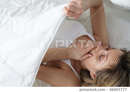 Young woman looking under covers and wondering 86665777