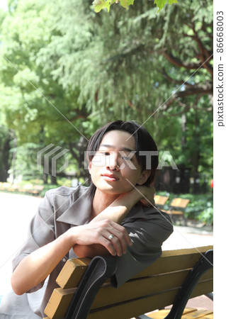 一個年輕人看著相機在公園裡放鬆 86668003