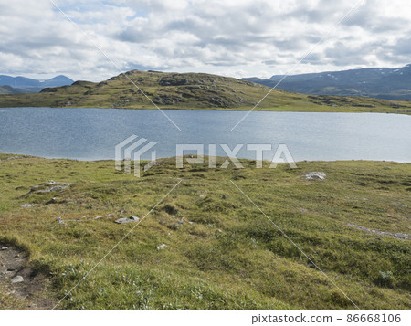 Beatiful northern landscape, tundra in Swedish Lapland with blue artic lake, green hills and mountains at Padjelantaleden hiking trail. Summer day, blue sky, white clouds Beatiful northern landscape, tundra in Swedish Lapland with blue artic lake, green hills and mountains at Padjelantaleden hiking trail. Summer day, blue sky, white clouds 86668106