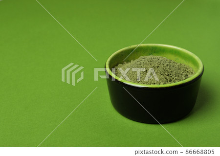 Bowl of matcha powder on green background Bowl of matcha powder on green background 86668805