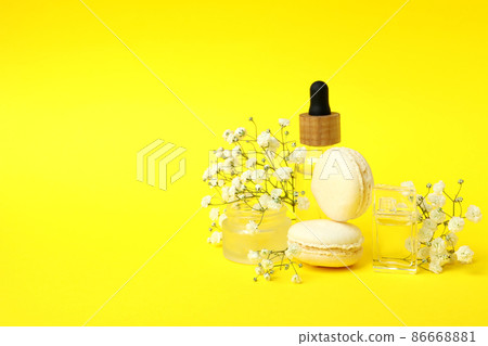 Cosmetics, macaroons and flowers on yellow background Cosmetics, macaroons and flowers on yellow background 86668881