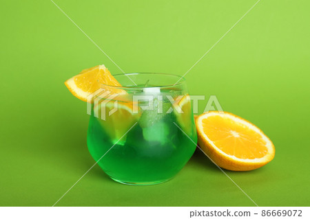 Glass of citrus cocktail and ingredients on green background Glass of citrus cocktail and ingredients on green background 86669072