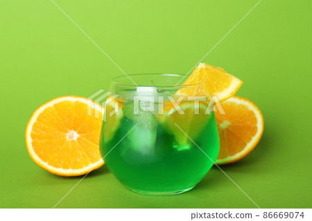 Glass of citrus cocktail and ingredients on green background Glass of citrus cocktail and ingredients on green background 86669074