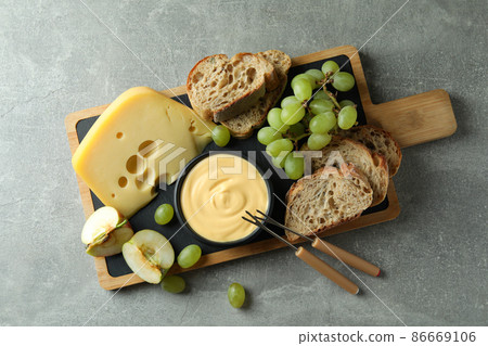Concept of delicious food with fondue on gray textured table Concept of delicious food with fondue on gray textured table 86669106