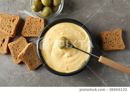 Concept of delicious food with fondue on gray textured table Concept of delicious food with fondue on gray textured table 86669120