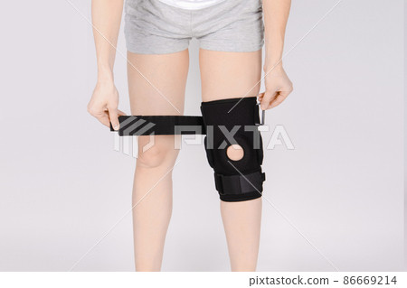 Knee Support Brace on leg isolated on white background. Elastic orthopedic orthosis. Anatomic braces for knee fixation, injuries and pain. Protective knee joint bandage sleeve. Trauma, rehabilitation. 86669214