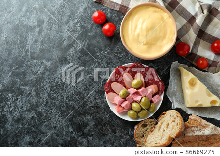 Concept of delicious food with fondue on black smokey table Concept of delicious food with fondue on black smokey table 86669275