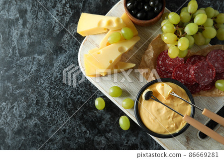 Concept of delicious food with fondue on black smokey table Concept of delicious food with fondue on black smokey table 86669281